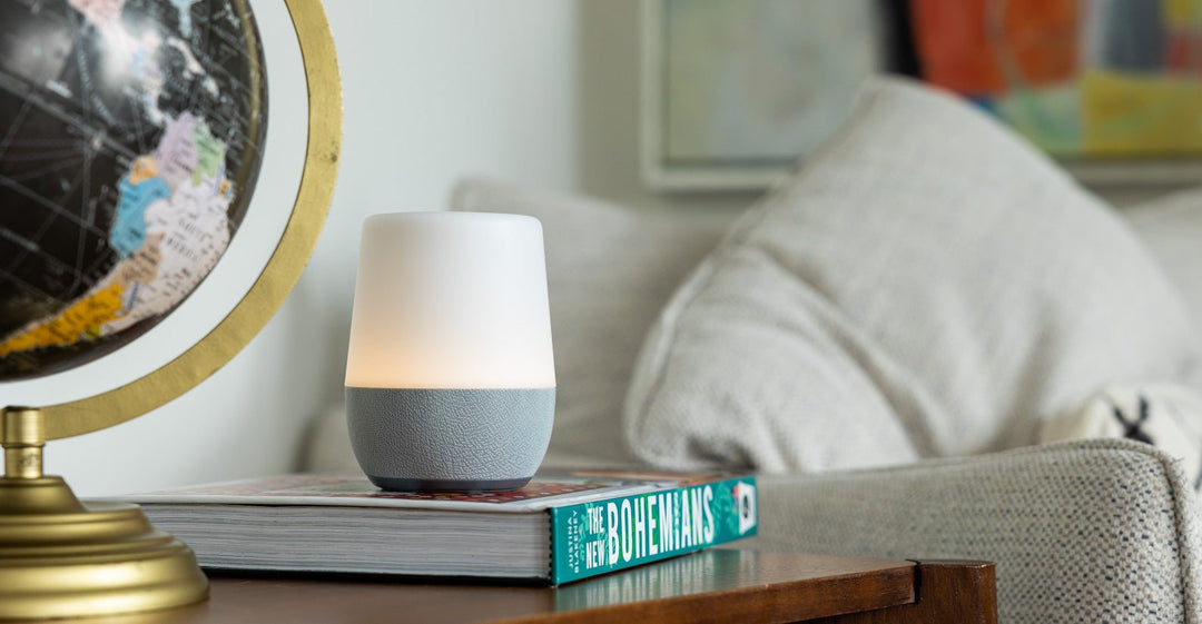 Front view of sleep sound machine with fabric base and soft-glow nightlight on a book beside a couch