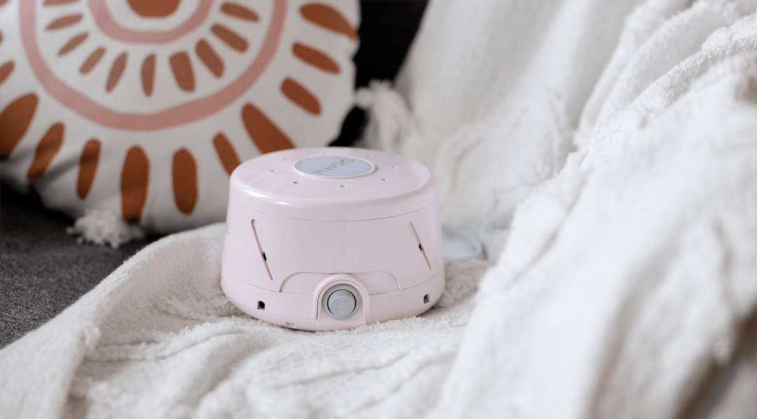 Front view of pink Yogasleep white noise machine showing top brand label and front power dial on a white blanket