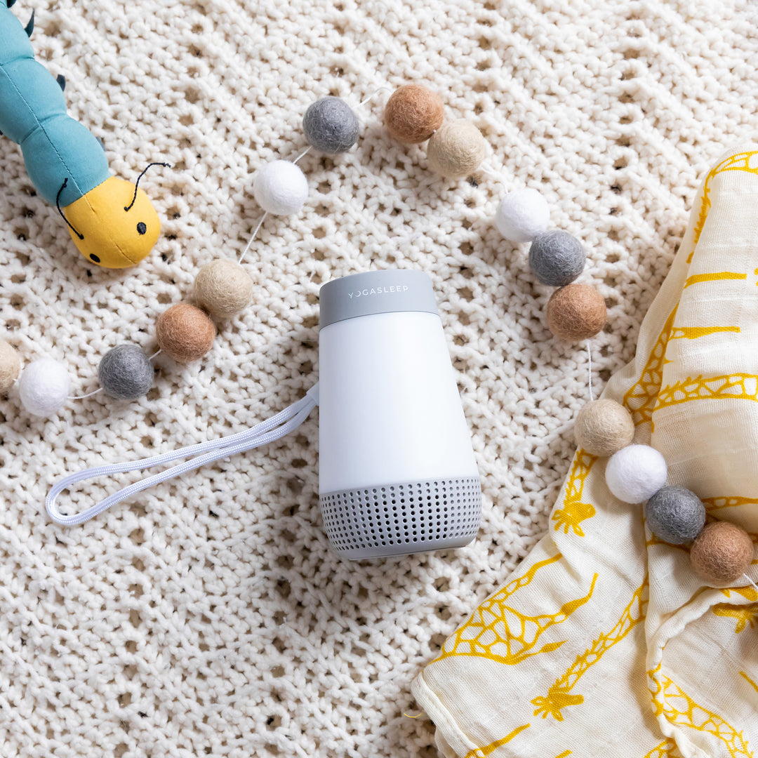 Close-up of Baby Soother showing its white cylindrical design on a textured knitted blanket